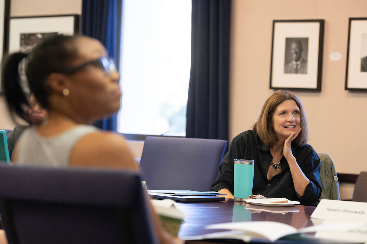 Two women in a conference room, one smiling and engaged, other blurred in foreground.